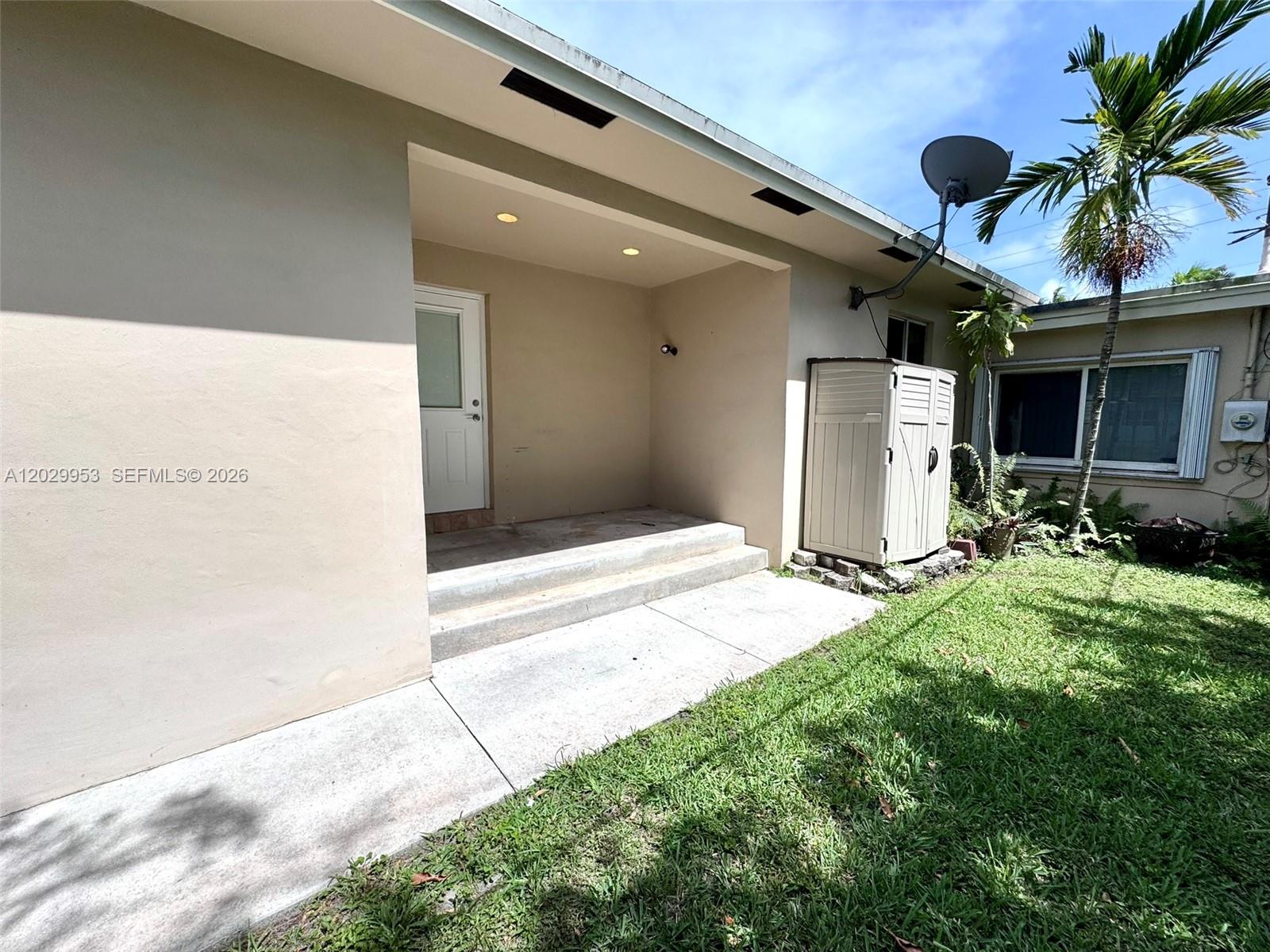 A concrete patio with two steps leads to a white door under a recessed porch — 1419 Garfield St, Hollywood FL 33020, HOLLYWOOD, FL
