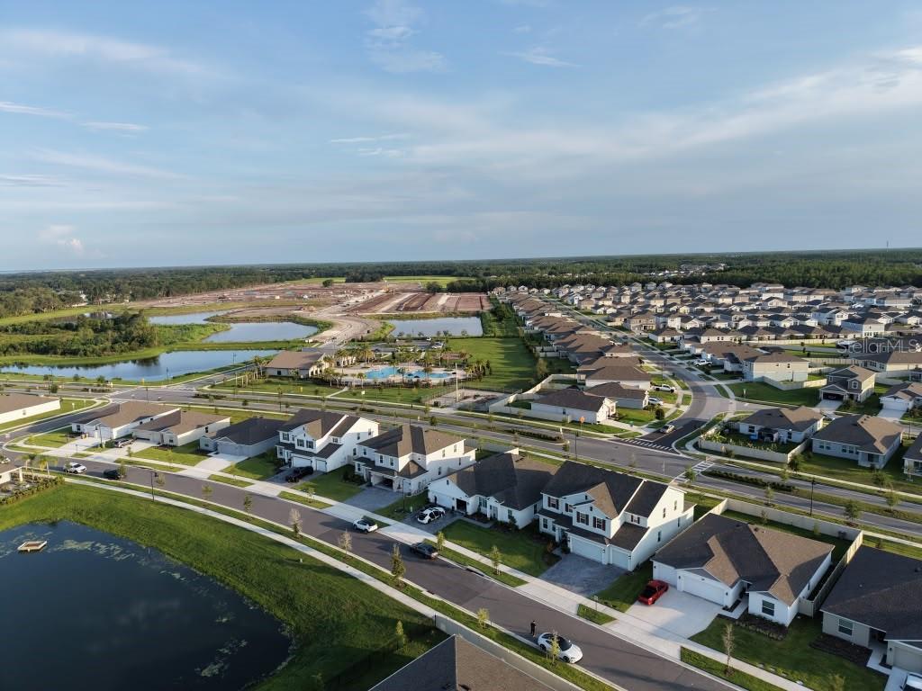 An aerial view shows a suburban neighborhood with houses, a community pool, and retention ponds — 4170 GOOSEBERRY TRAIL, KISSIMMEE, FL