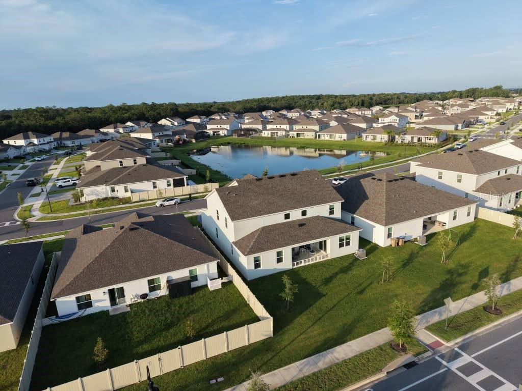 An aerial view of a suburban neighborhood featuring houses with fenced yards and a pond — 4170 GOOSEBERRY TRAIL, KISSIMMEE, FL