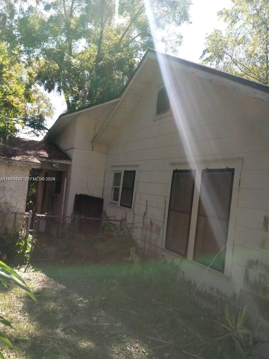The exterior of a weathered, white-sided house with a gabled roof and overgrown yard — 331 NE 9 AVE, Ocala FL 34470, OCALA, FL