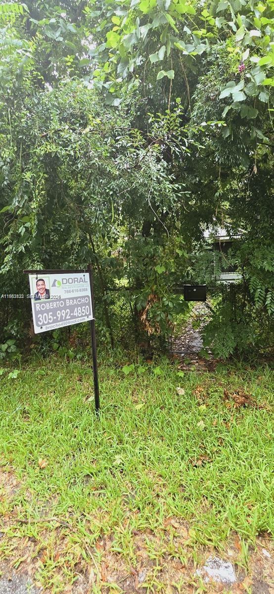 A real estate sign stands in front of a heavily overgrown, fenced residential property — 331 NE 9 AVE, Ocala FL 34470, OCALA, FL