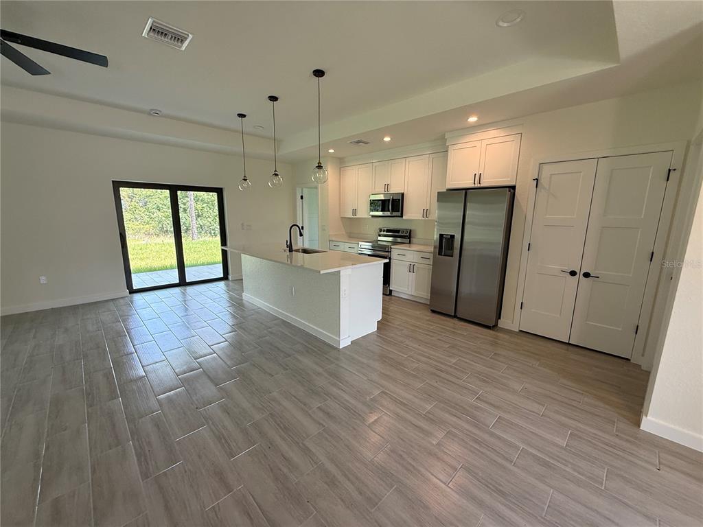 A modern kitchen features white cabinetry, stainless steel appliances, a center island, and tile flooring — 3764 CINDERELLA ROAD, NORTH PORT, FL
