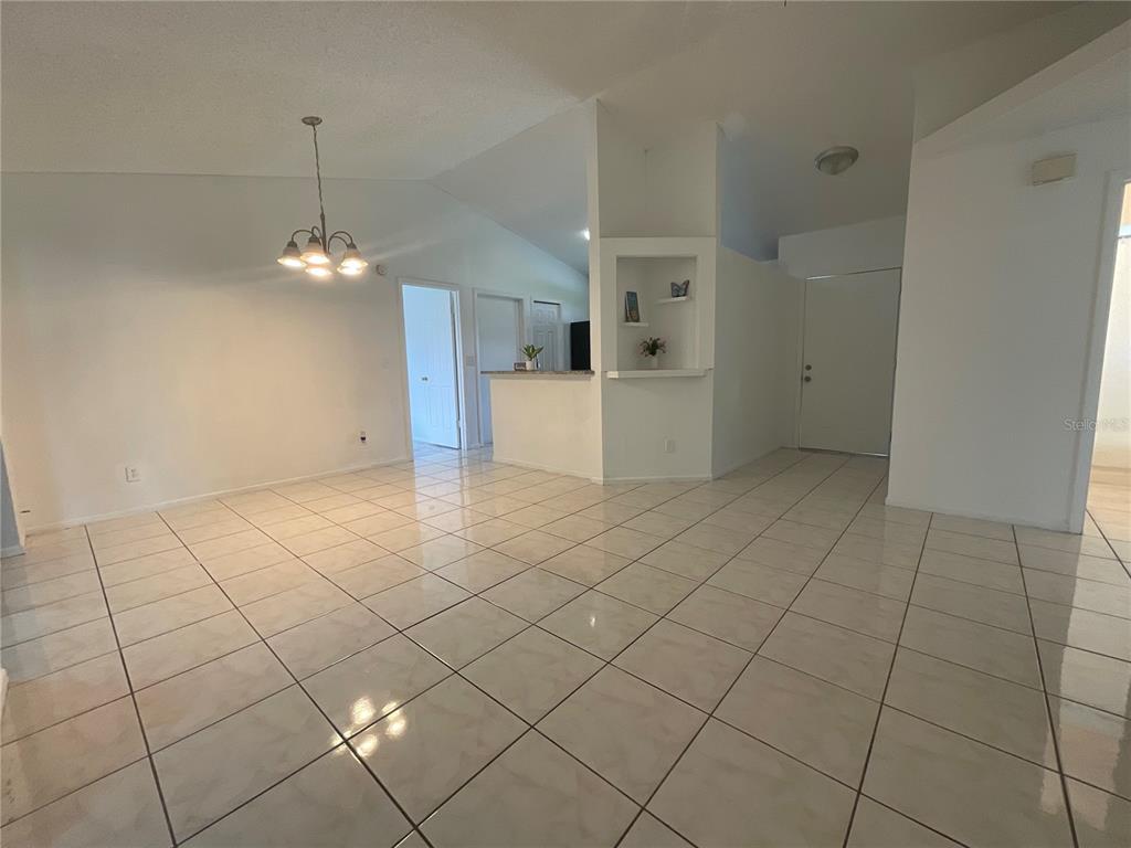 A bright, open-concept living and dining area features white tile flooring and vaulted ceilings — 340 CHIQUITA COURT, KISSIMMEE, FL