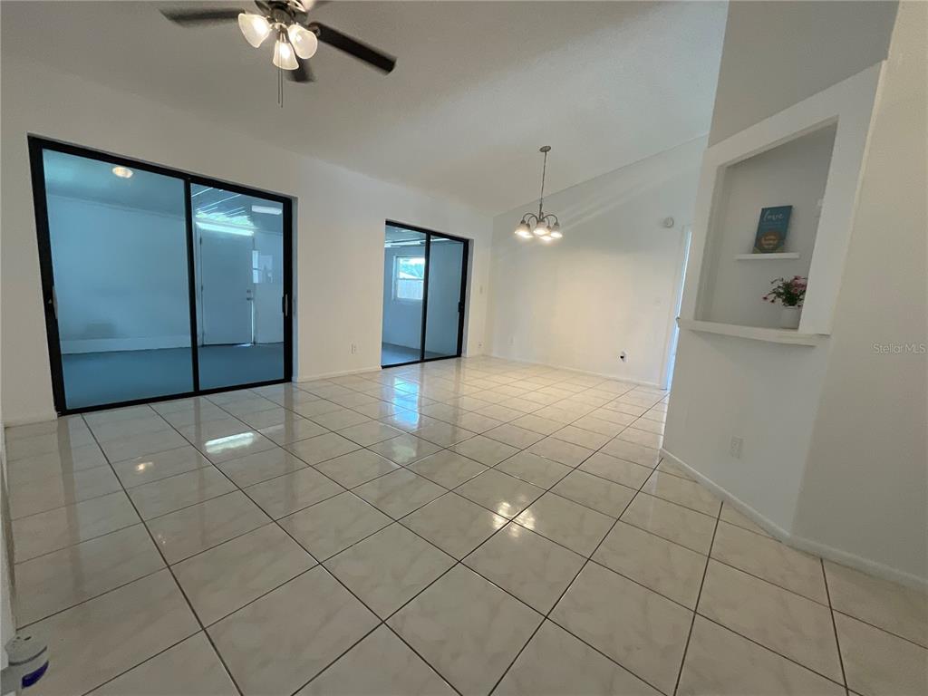 A bright room features light-colored tile flooring, a ceiling fan, and two sliding glass doors — 340 CHIQUITA COURT, KISSIMMEE, FL