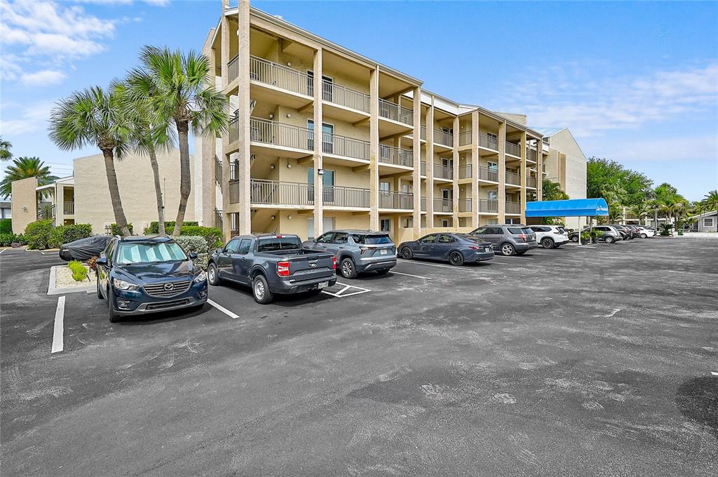 A multi-story apartment building with a parking lot in front featuring several parked cars — 845 BENJAMIN FRANKLIN DRIVE UNIT 402, SARASOTA, FL