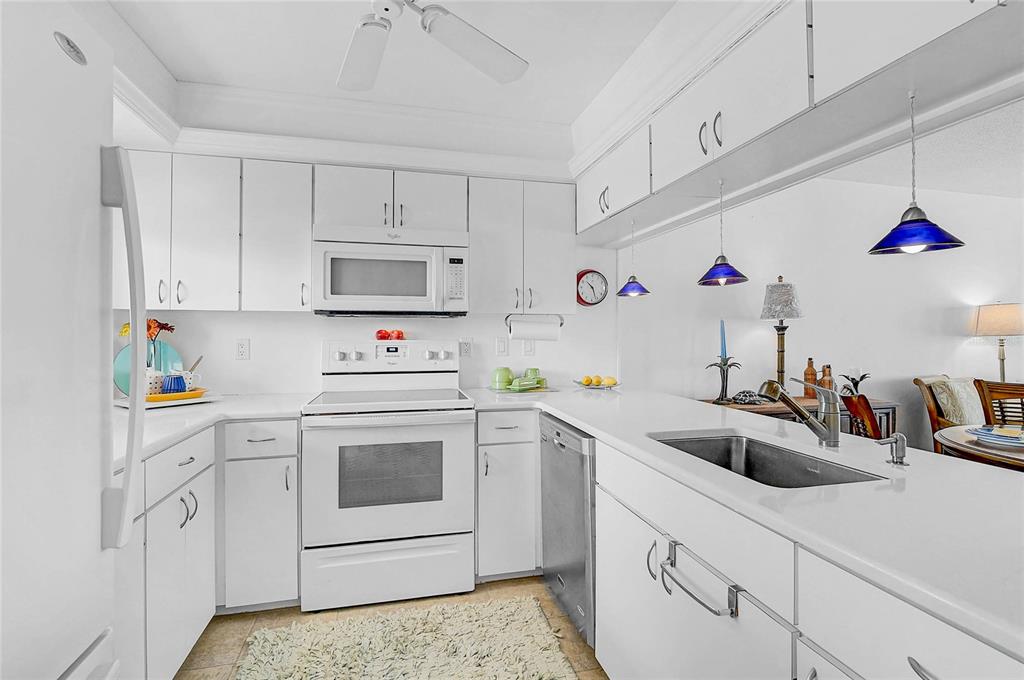 A white kitchen features white cabinetry, white appliances, and a stainless steel sink — 845 BENJAMIN FRANKLIN DRIVE UNIT 402, SARASOTA, FL