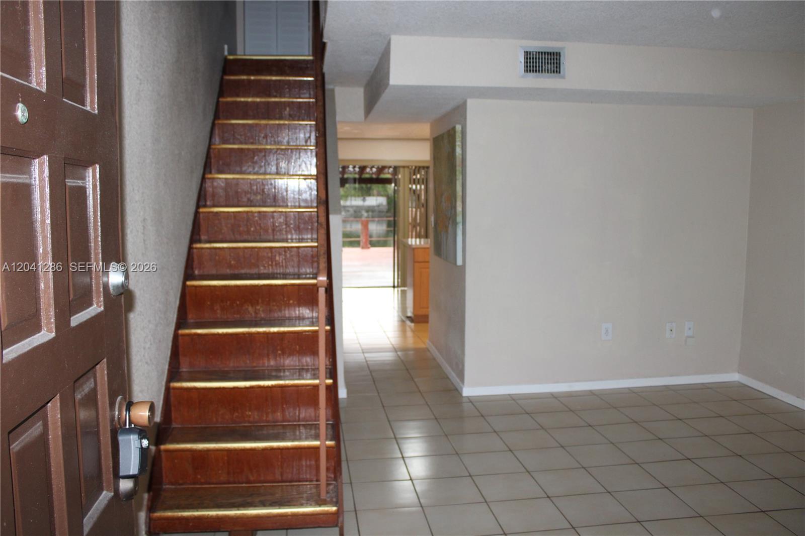 A staircase with wooden steps leads upward next to a tiled room with a doorway — 5446 W 26th Ave # 20, Hialeah FL 33016, HIALEAH, FL