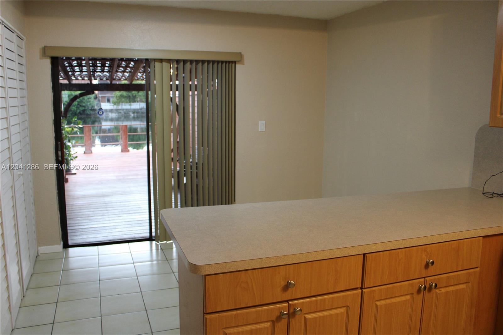 A kitchen counter overlooks a dining area with a sliding glass door leading to a deck — 5446 W 26th Ave # 20, Hialeah FL 33016, HIALEAH, FL