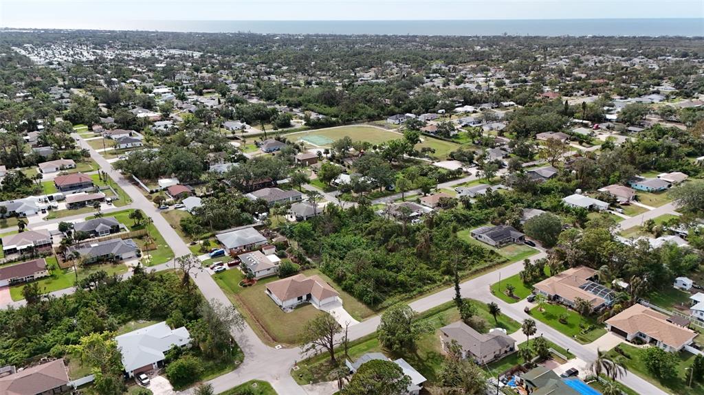 An aerial view shows a suburban neighborhood with houses, streets, and a central wooded lot — LOTS 3115 & 3116 CYPRESS ROAD, VENICE, FL