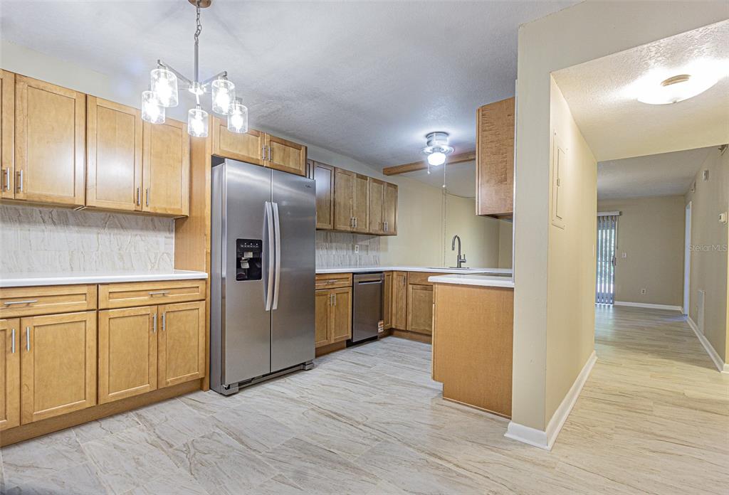A kitchen features light wood cabinets, stainless steel appliances, and light-colored tile flooring — 11201 122ND AVENUE UNIT 197, LARGO, FL