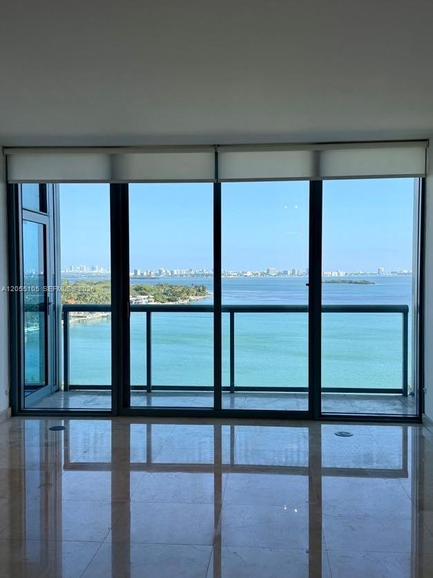 A room with polished tile floors features floor-to-ceiling windows overlooking a bay and city skyline — 601 NE 36th St # 1311, Miami FL 33137, MIAMI, FL