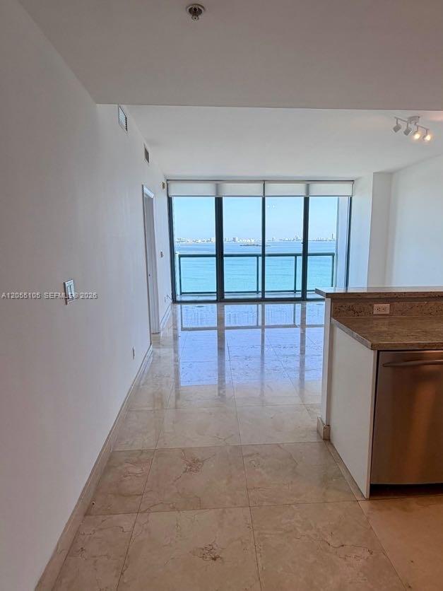 A kitchen with granite countertops overlooks a living area with tile floors and balcony views — 601 NE 36th St # 1311, Miami FL 33137, MIAMI, FL