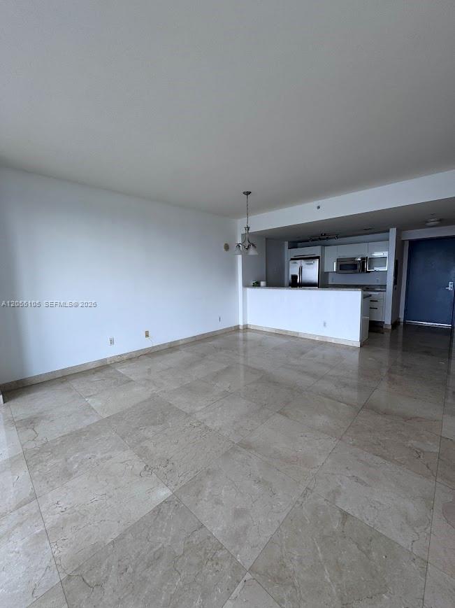 An open-concept living area features large beige floor tiles and a kitchen with white cabinetry — 601 NE 36th St # 1311, Miami FL 33137, MIAMI, FL