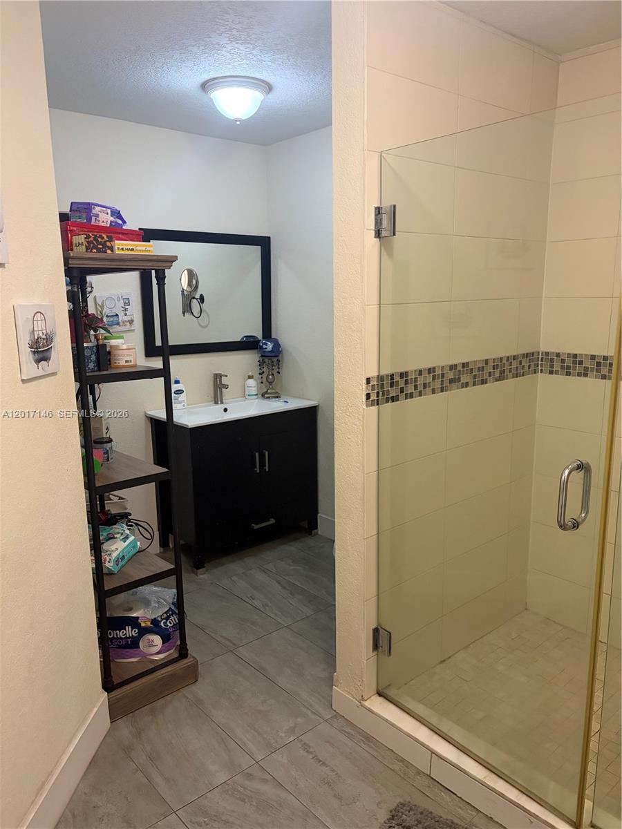 A bathroom features a black vanity, a glass-enclosed shower, and a tall metal shelving unit — 6725 NW 174th Ter # 12, Hialeah FL 33015, HIALEAH, FL