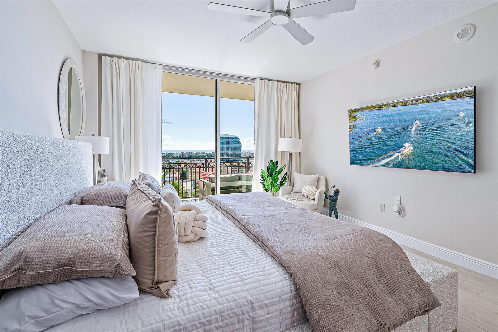 A bedroom features a king bed, a wall-mounted television, and a balcony with city views — 550 Okeechobee Boulevard # 1615, West Palm Beach FL 33401, WEST PALM BEACH, FL