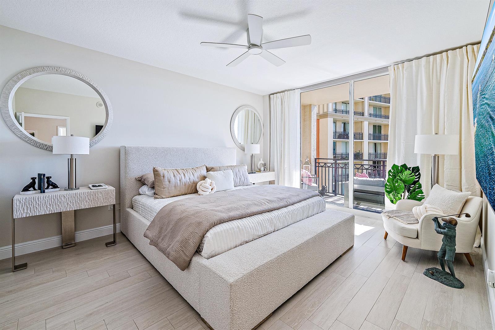 A bedroom features a textured bed, a console table with a mirror, and a balcony view — 550 Okeechobee Boulevard # 1615, West Palm Beach FL 33401, WEST PALM BEACH, FL
