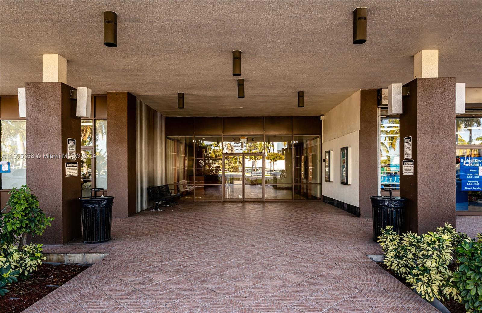 A covered entrance features a tiled walkway leading to glass doors between two brown pillars — 2500 E Hallandale Beach Blvd, Hallandale Beach FL 33009, HALLANDALE BEACH, FL