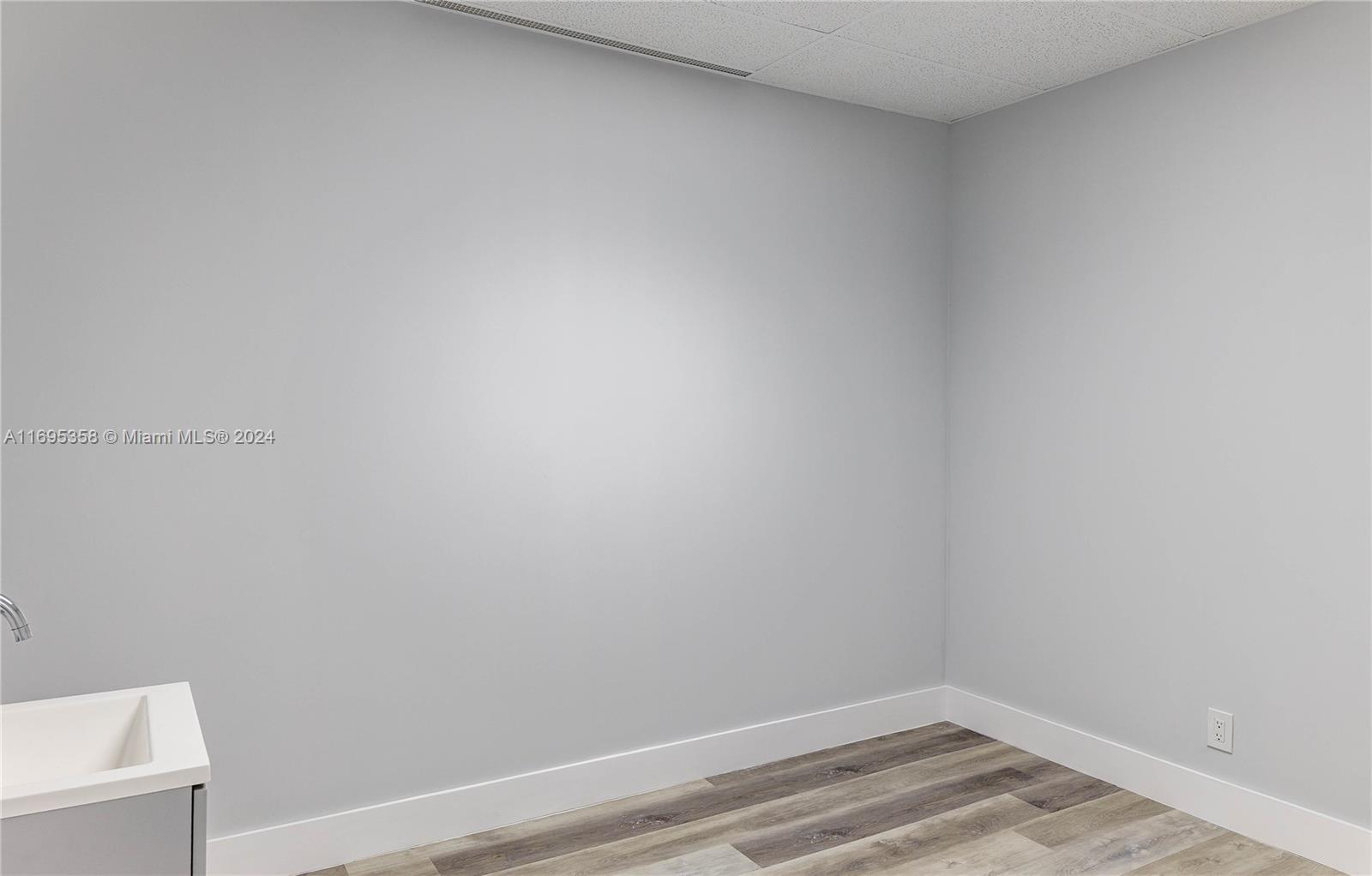 A corner of a room features light gray walls, wood-look flooring, and a small sink — 2500 E Hallandale Beach Blvd, Hallandale Beach FL 33009, HALLANDALE BEACH, FL
