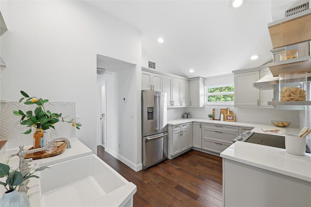 A kitchen with light gray cabinets, stainless steel appliances, white countertops, and dark wood floors — 7 GEORGIA AVENUE, CRYSTAL BEACH, FL