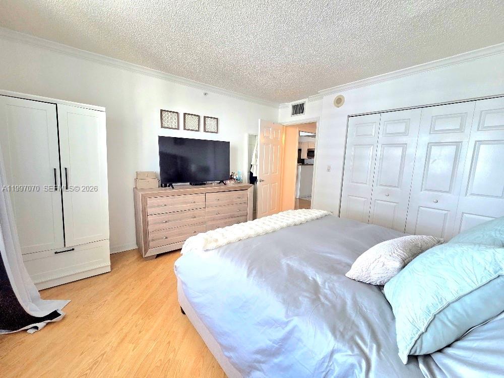 An empty room features light wood-look flooring, white walls, and an open kitchen pass-through — 1155 Brickell Bay Dr # 2006, Miami FL 33131, MIAMI, FL