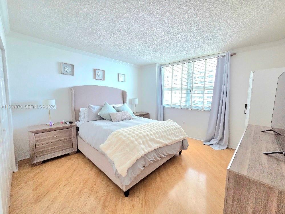 An empty living room features light wood-look flooring, white walls, and a popcorn ceiling — 1155 Brickell Bay Dr # 2006, Miami FL 33131, MIAMI, FL