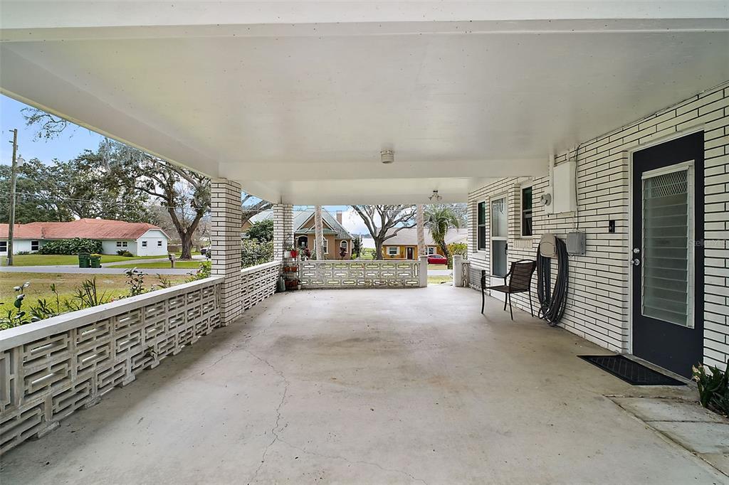 A covered concrete patio features white brick walls, decorative block railings, and a dark door — 803 N SHORE DRIVE, LEESBURG, FL