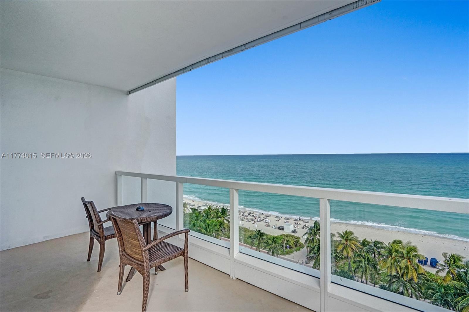 A balcony with a small table and two chairs overlooks the beach and ocean — 4391 Collins Ave, Miami Beach FL 33140, MIAMI BEACH, FL