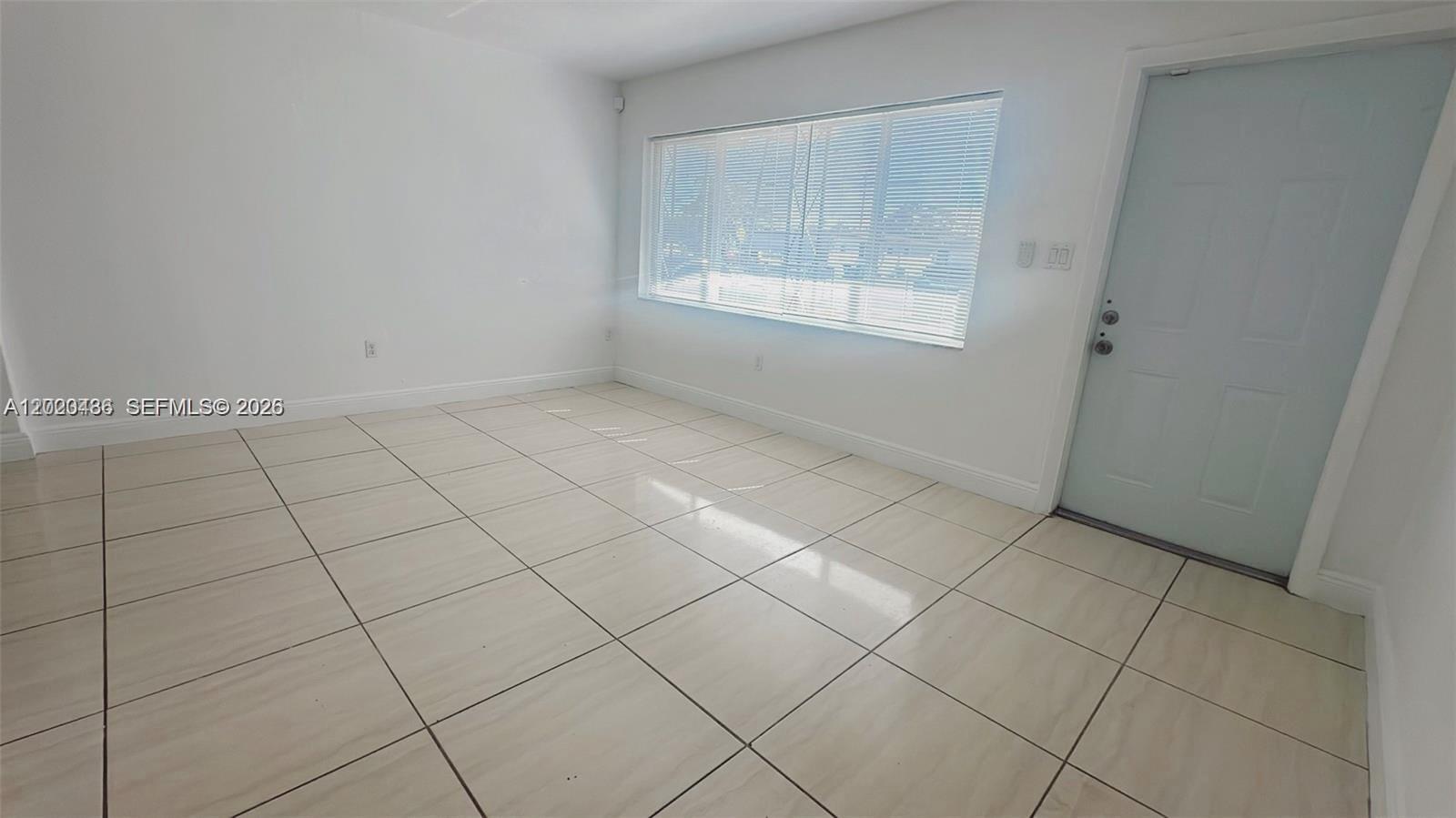 A fenced backyard features a grassy lawn, a white door, and an outdoor air conditioning unit — 2125 NW 66th St # 2, Miami FL 33147, MIAMI, FL