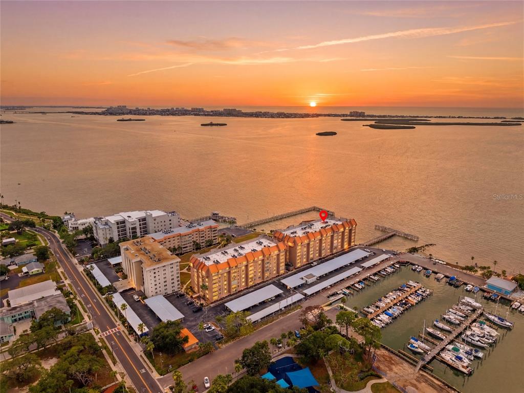 An aerial view shows a waterfront apartment complex with a marina at sunset — 634 EDGEWATER DRIVE UNIT 844, DUNEDIN, FL