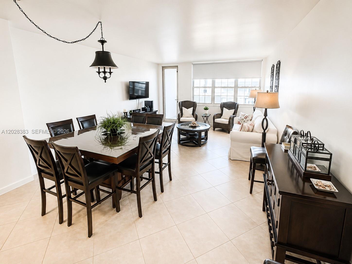 A dining and living area features tile flooring, dark wood furniture, and a white sofa — 100 Lincoln Rd # 602, Miami Beach FL 33139, MIAMI BEACH, FL