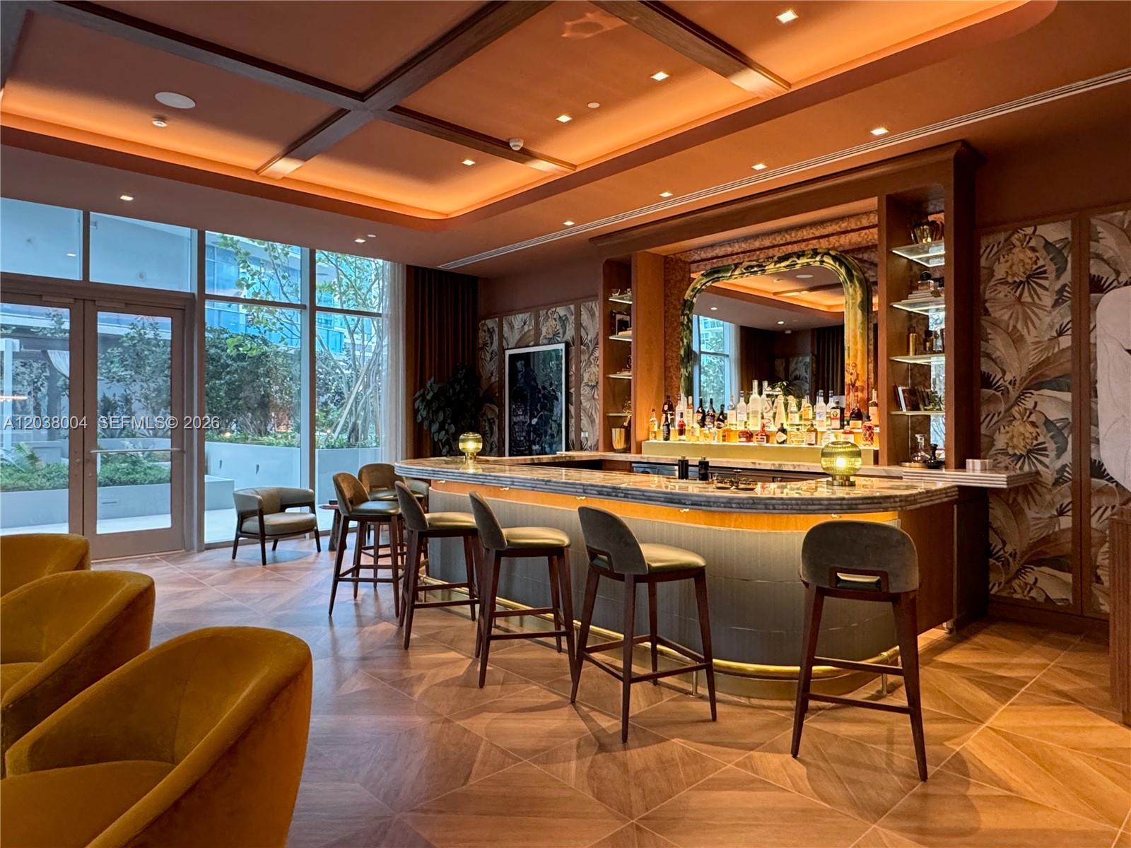 A modern bar area features a curved marble counter, upholstered stools, and patterned wallpaper — 77 SE 5th St # 4002, Miami FL 33131, MIAMI, FL