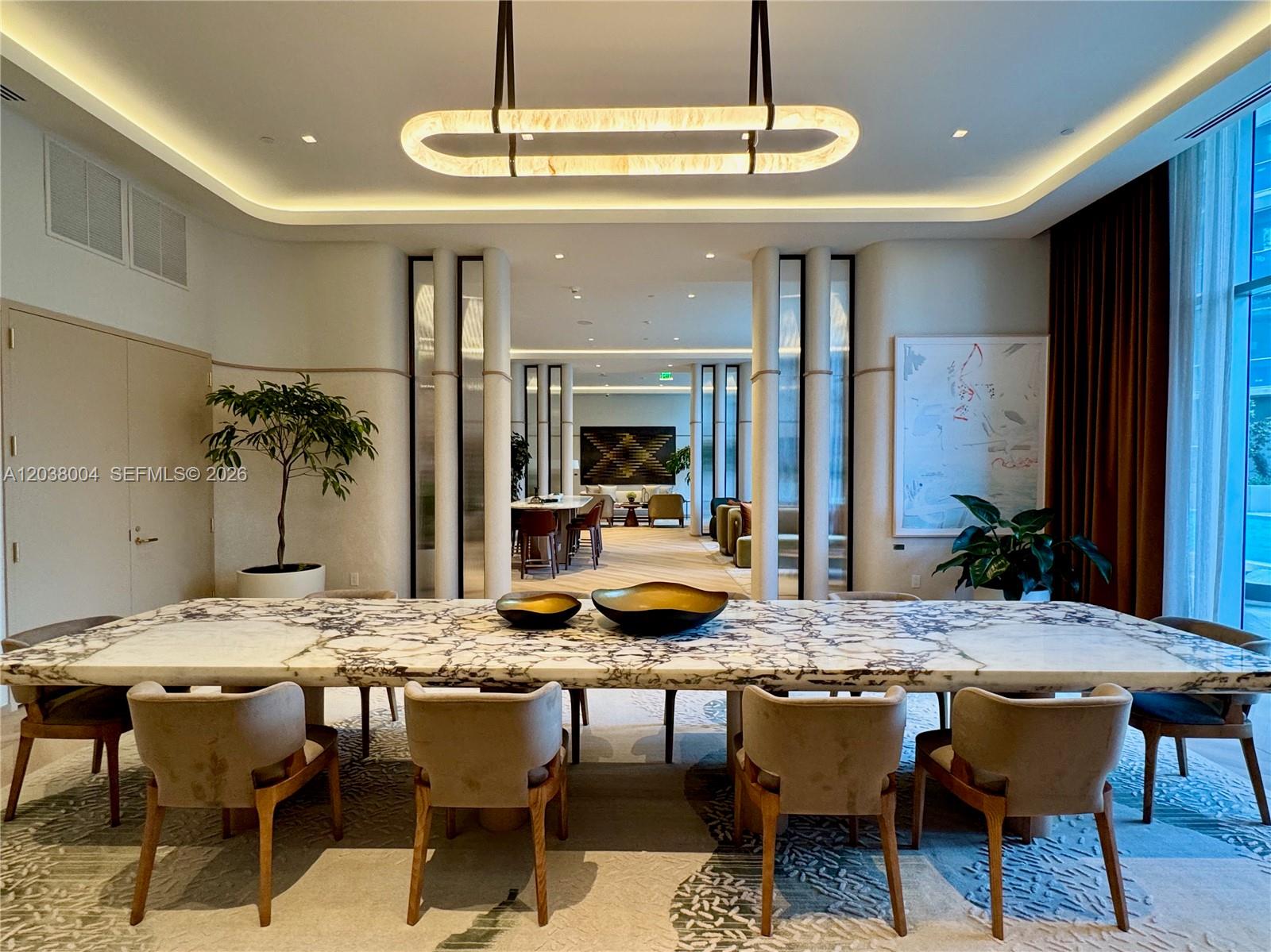 A dining room features a long marble table, upholstered chairs, and a modern light fixture — 77 SE 5th St # 4002, Miami FL 33131, MIAMI, FL
