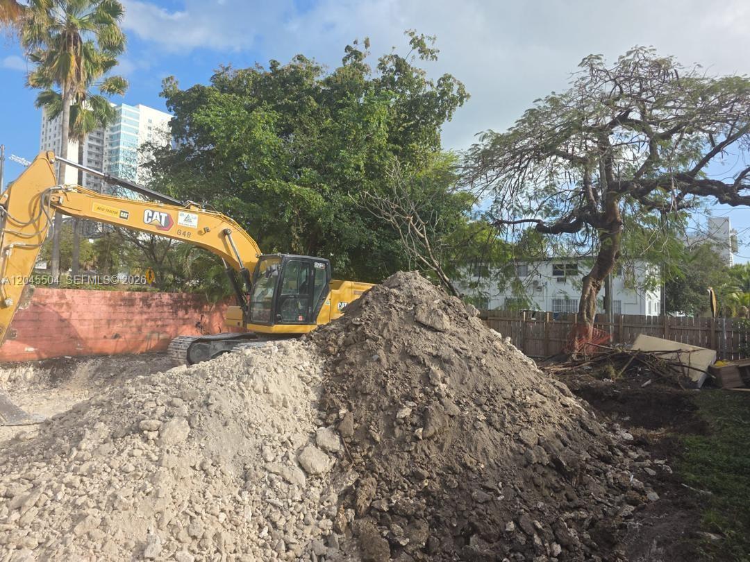 A yellow Caterpillar excavator sits next to a large pile of dirt and rocks — 933 SW 4th Ave, Miami FL 33130, MIAMI, FL