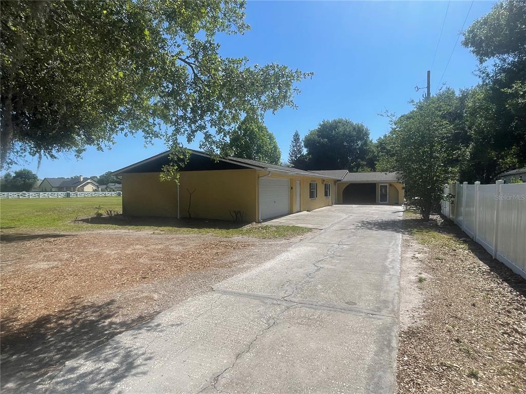 A yellow single-story house with a garage and a concrete driveway under a clear sky — 3575 MICHIGAN AVENUE, ST CLOUD, FL