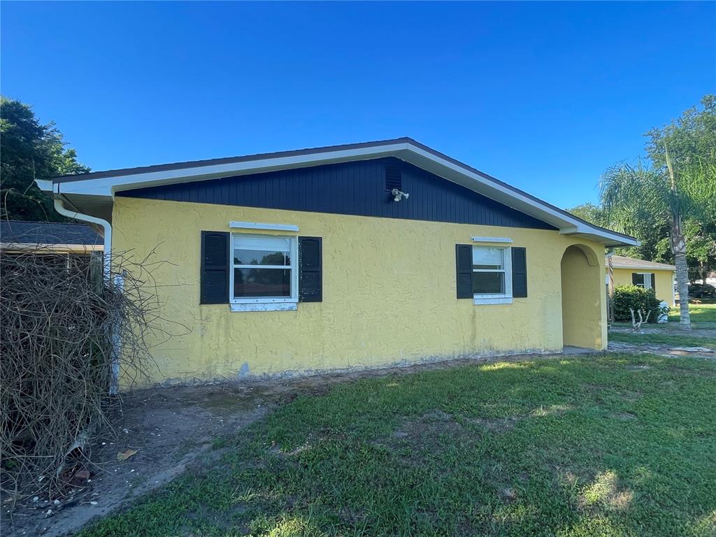 A yellow, single-story house with a dark blue gable and black window shutters — 3575 MICHIGAN AVENUE, ST CLOUD, FL
