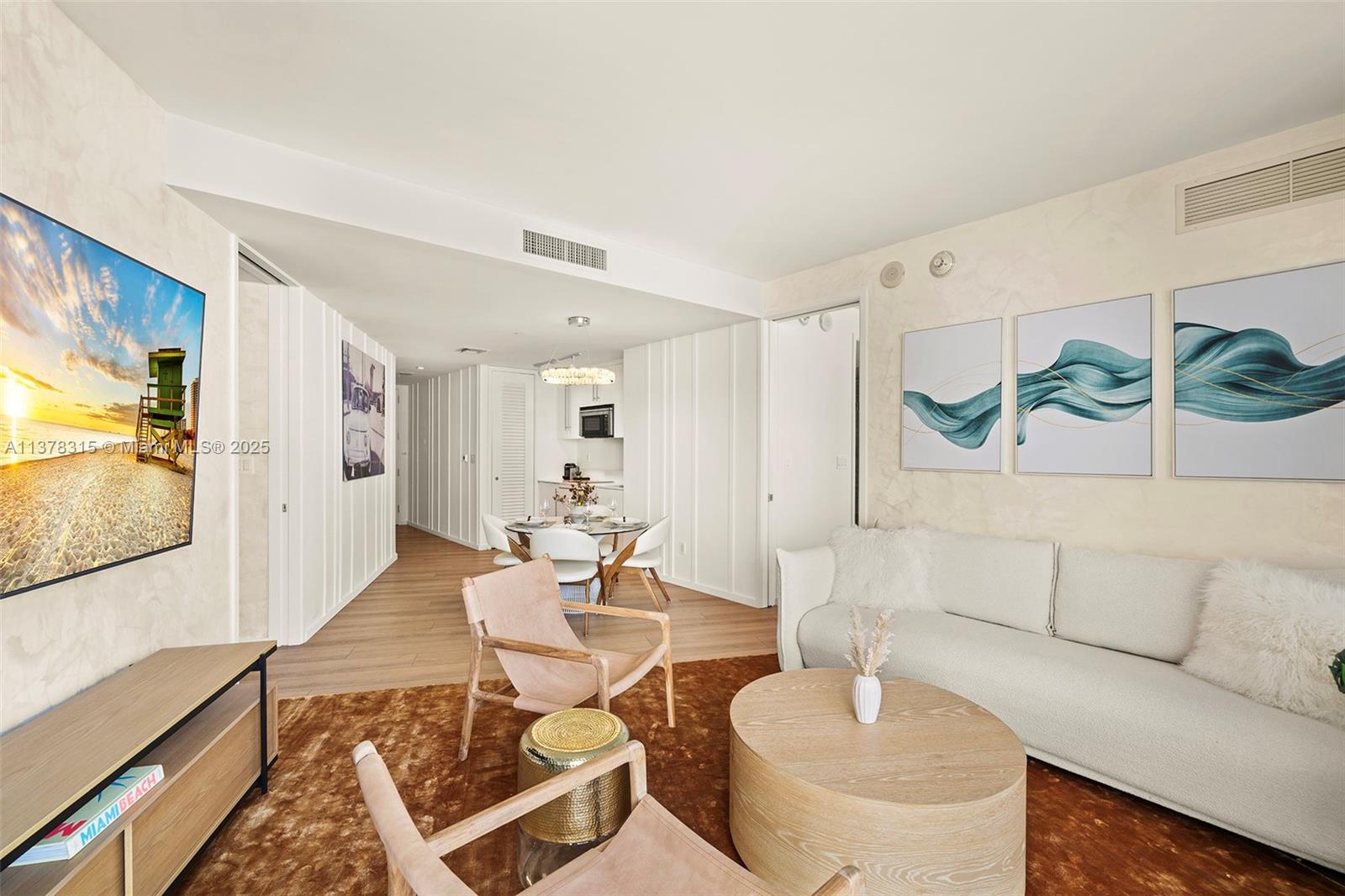 A living room with a white sofa, round coffee table, and dining area in the background — 2201 Collins Ave # 811, Miami Beach FL 33139, MIAMI BEACH, FL