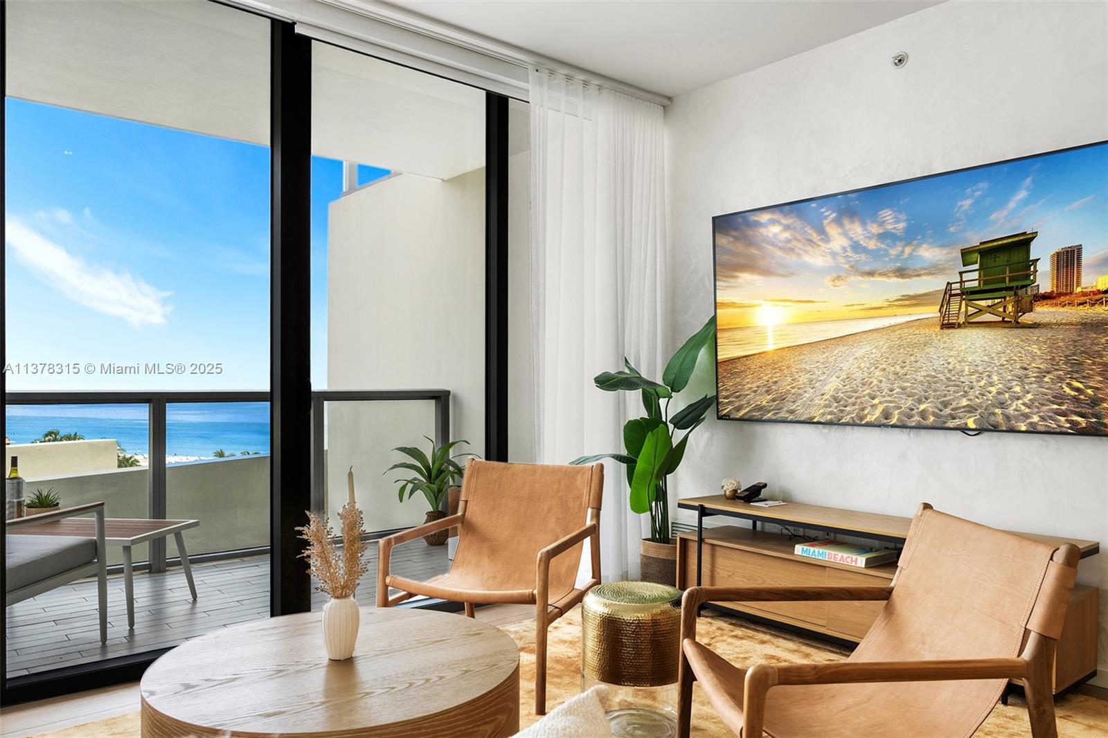 A living room features two leather chairs, a wooden coffee table, and a balcony view — 2201 Collins Ave # 811, Miami Beach FL 33139, MIAMI BEACH, FL