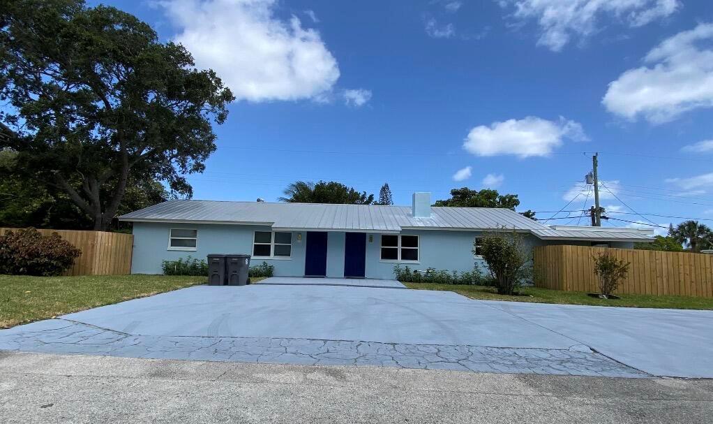 A light blue single-story duplex with a metal roof and a large paved driveway — 1867 Windsor Drive, North Palm Beach FL 33408, NORTH PALM BEACH, FL