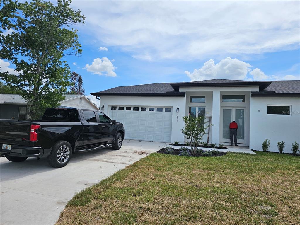 A view of a residential driveway, a white garage, and a neighboring house — 292 GARDENIA ROAD, KISSIMMEE, FL