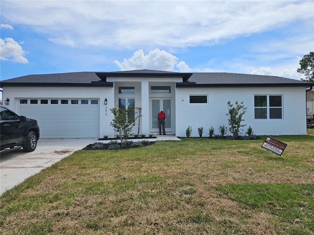 A modern kitchen features white cabinets, marble-look tile floors, a center island, and black appliances — 292 GARDENIA ROAD, KISSIMMEE, FL