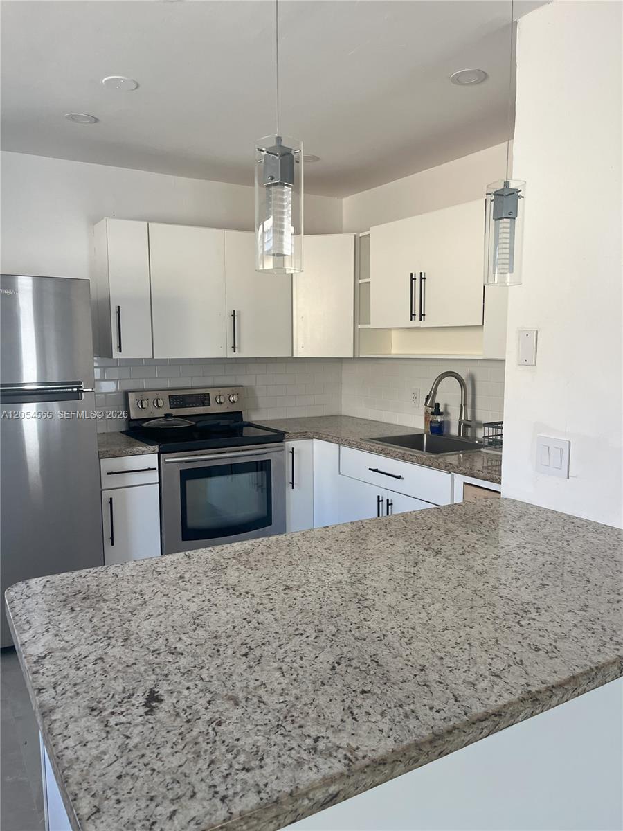 A kitchen features white cabinets, granite countertops, stainless steel appliances, and two hanging pendant lights — 2783 SW 33rd Ave # 2783, Miami FL 33133, MIAMI, FL