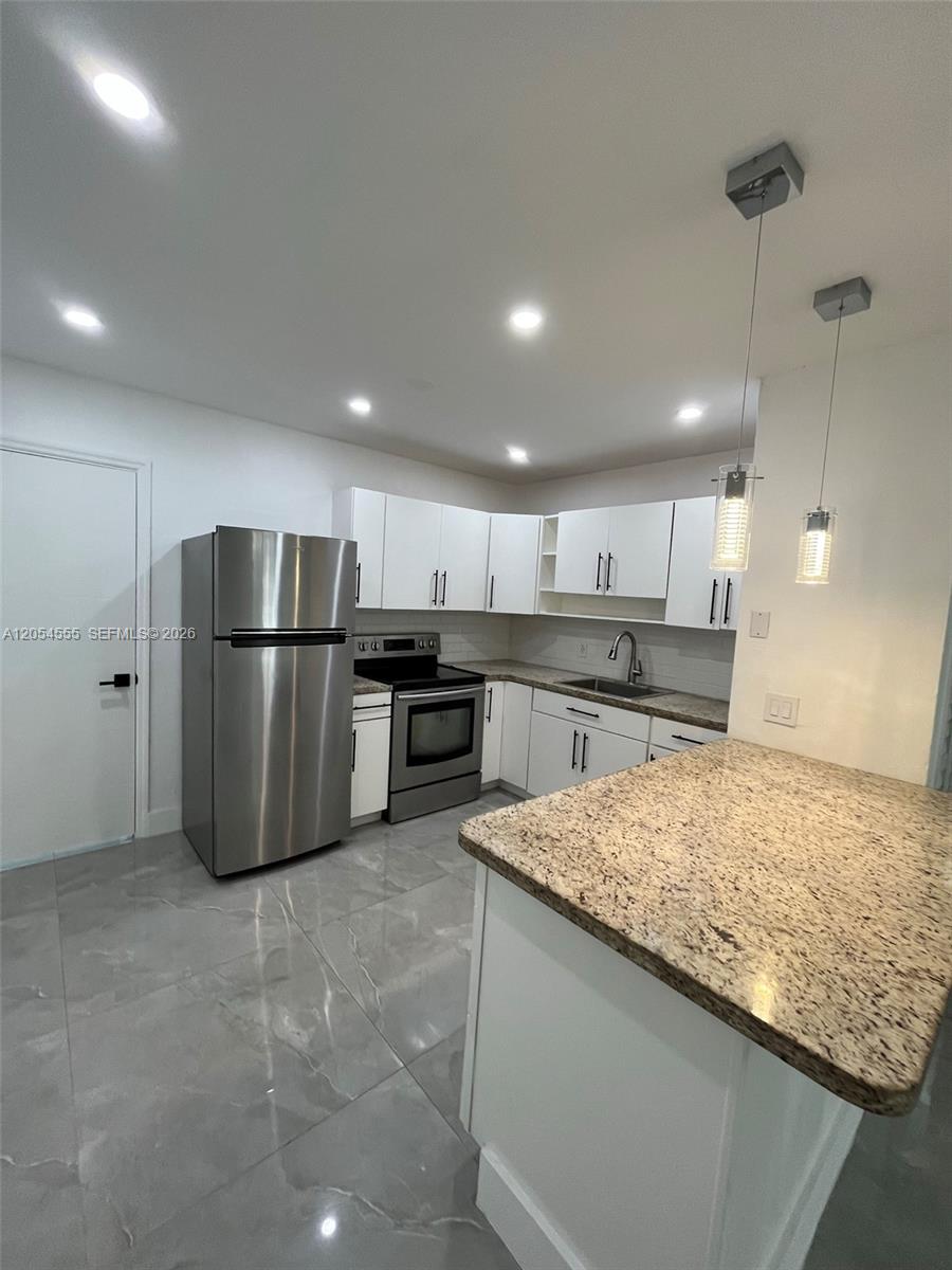 A kitchen features white cabinets, stainless steel appliances, granite countertops, and light gray tile flooring — 2783 SW 33rd Ave # 2783, Miami FL 33133, MIAMI, FL
