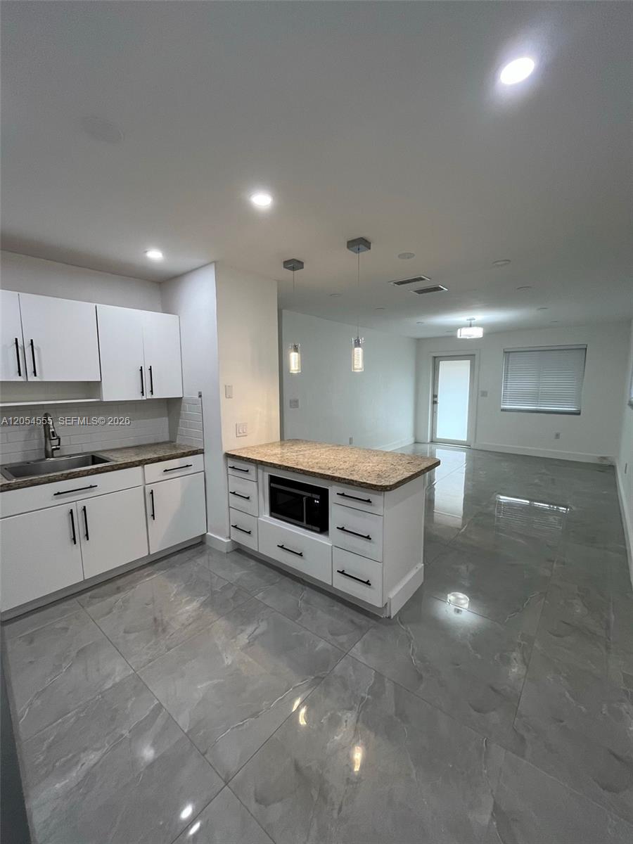 A kitchen features white cabinets, granite countertops, a built-in microwave, and gray tile flooring — 2783 SW 33rd Ave # 2783, Miami FL 33133, MIAMI, FL