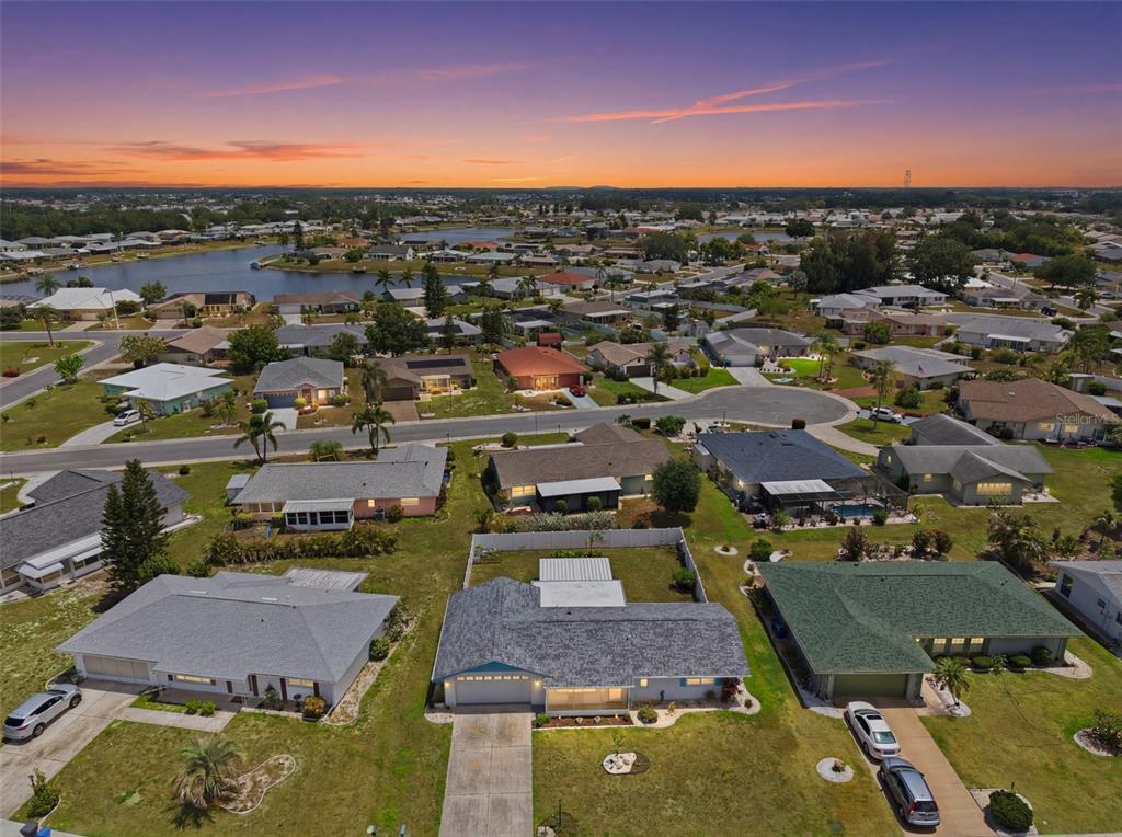An aerial view of a suburban neighborhood featuring single-story houses with lawns and a lake — 1739 COCO PALM CIRCLE, SUN CITY CENTER, FL