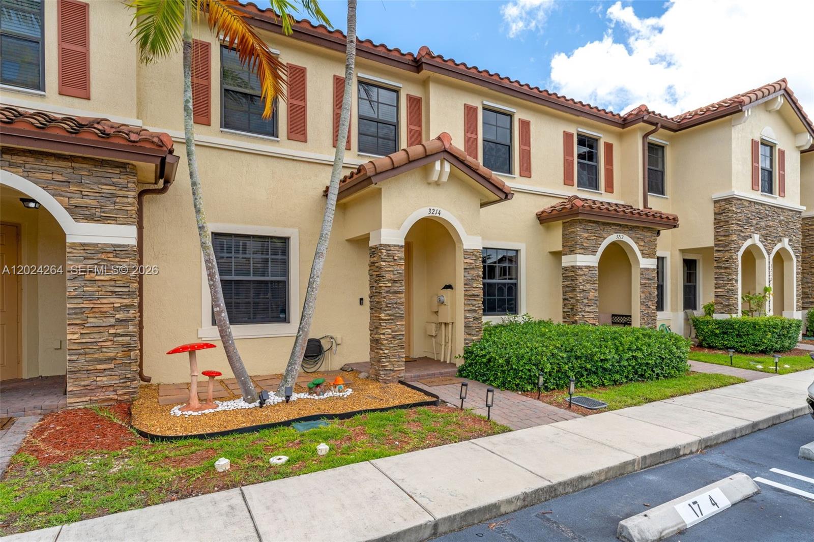 The exterior of a two-story townhouse features tan stucco walls, stone accents, and a tiled roof — 3214 SE 4th Ct, Homestead FL 33033, HOMESTEAD, FL