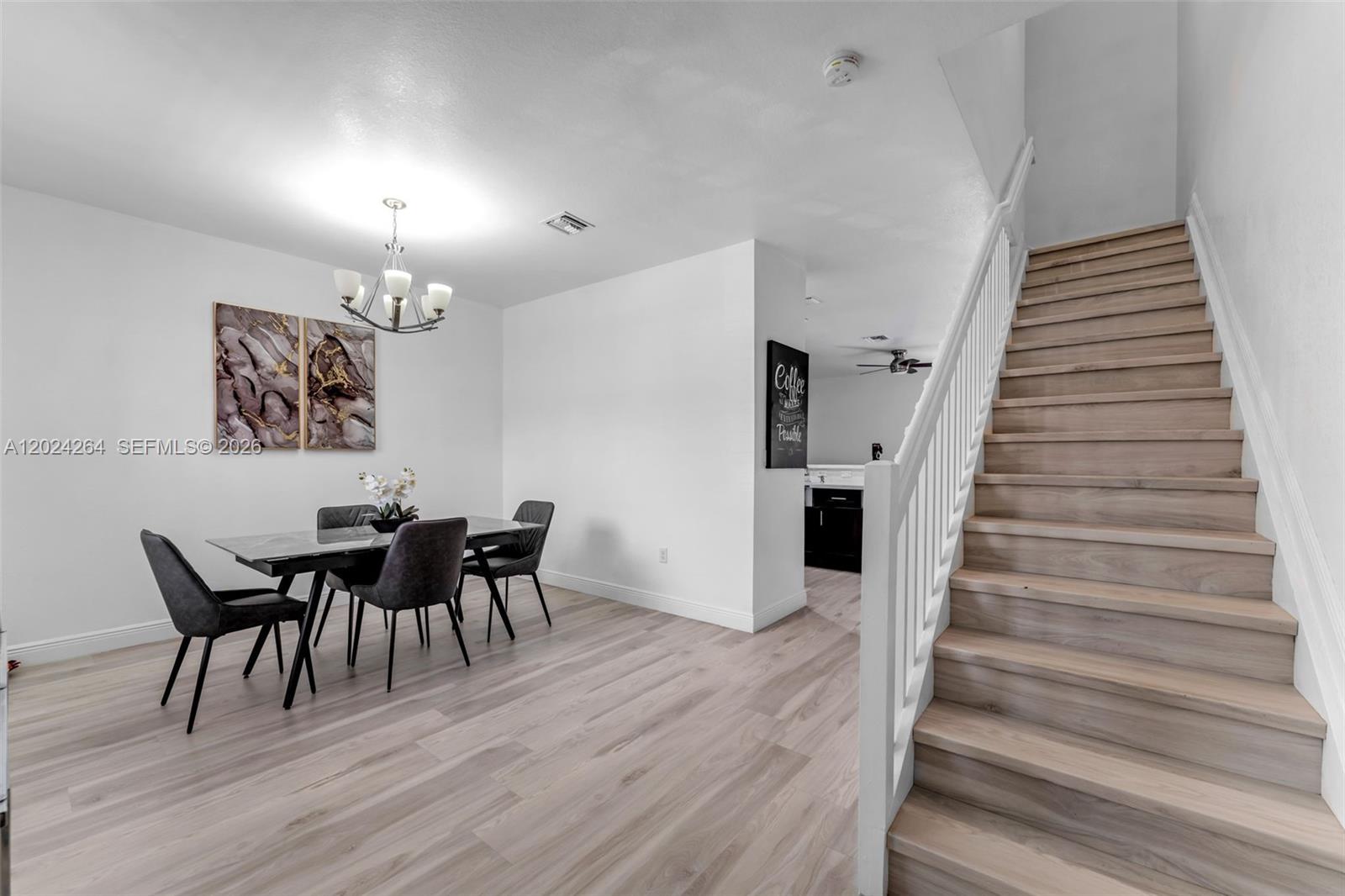A dining area with a table and chairs sits beside a staircase with wooden steps — 3214 SE 4th Ct, Homestead FL 33033, HOMESTEAD, FL
