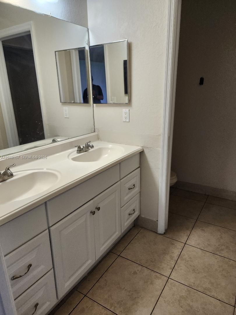 A bathroom features a white double-sink vanity with a large mirror and tiled flooring — 4740 SW 14, Lehigh Acres FL 33973, LEHIGH ACRES, FL