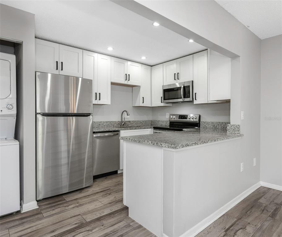 A kitchen with white cabinets, stainless steel appliances, and granite countertops — 1281 PINE RIDGE CIRCLE E UNIT A2, TARPON SPRINGS, FL