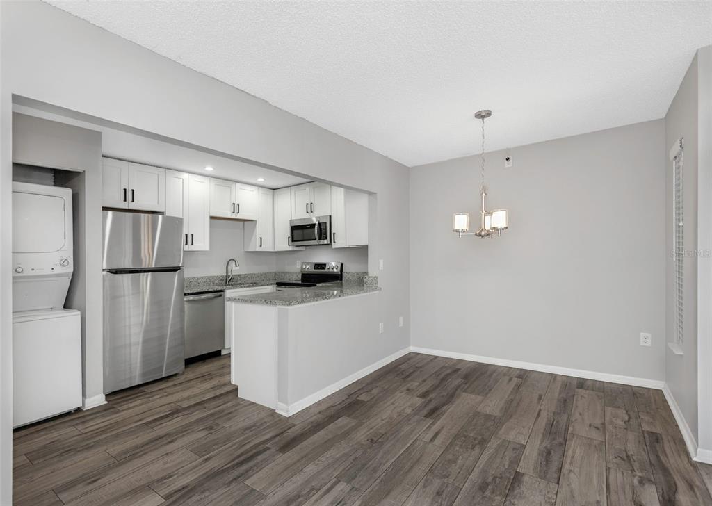 A kitchen with stainless steel appliances and white cabinets opens to a dining area — 1281 PINE RIDGE CIRCLE E UNIT A2, TARPON SPRINGS, FL