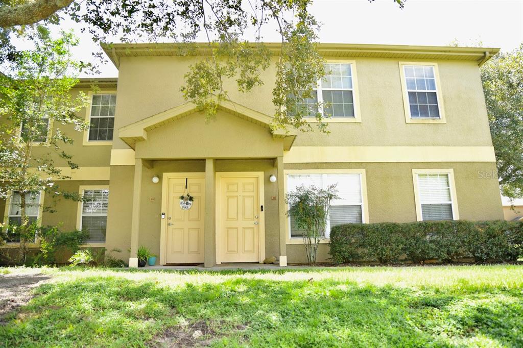 A two-story tan apartment building with two front doors and a small covered entryway — 36121 LAKE CHASE BOULEVARD UNIT 204, ZEPHYRHILLS, FL
